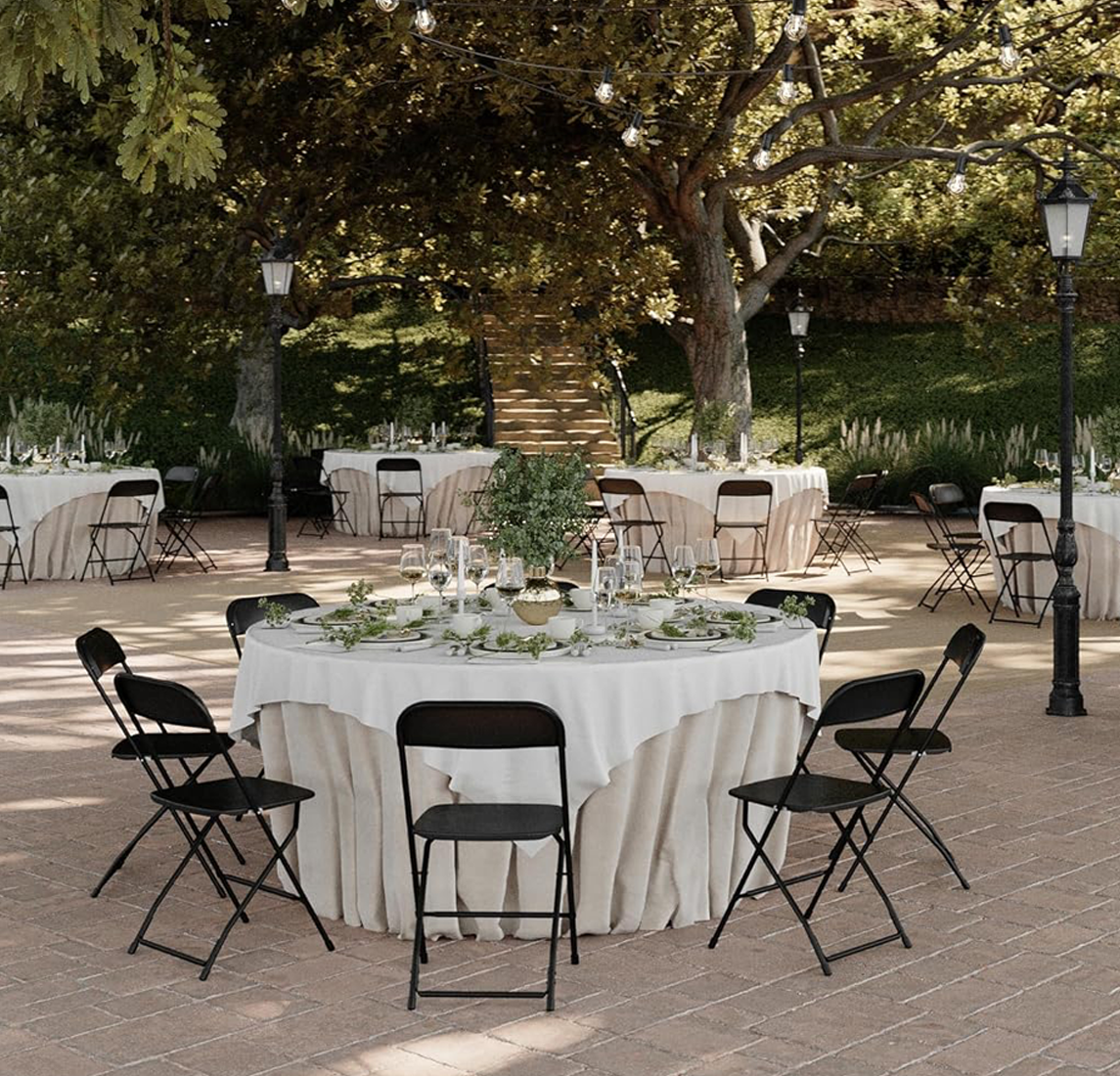 Black Folding Chairs at an Outdoor Wedding Reception Black commercial folding chairs set around round banquet tables at an outdoor wedding reception with string lights.