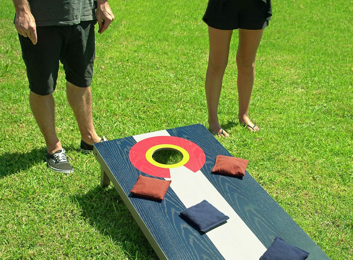 Colorado Flag Cornhole Board Rental in Action | Party For Less Rentals Aurora Denver CO Party For Less Rentals Colorado flag wood cornhole board with bean bags on grass Aurora Denver Colorado
